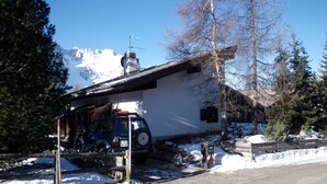 A white building with a sloped roof, a chimney, and a parked vehicle in front. - Chalet in Carezza al Lago (Carezza Al Lago)