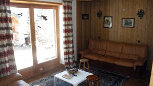 A cozy living room with a brown leather sofa, a white coffee table, and a patterned rug. - Chalet in Carezza al Lago (Carezza Al Lago)