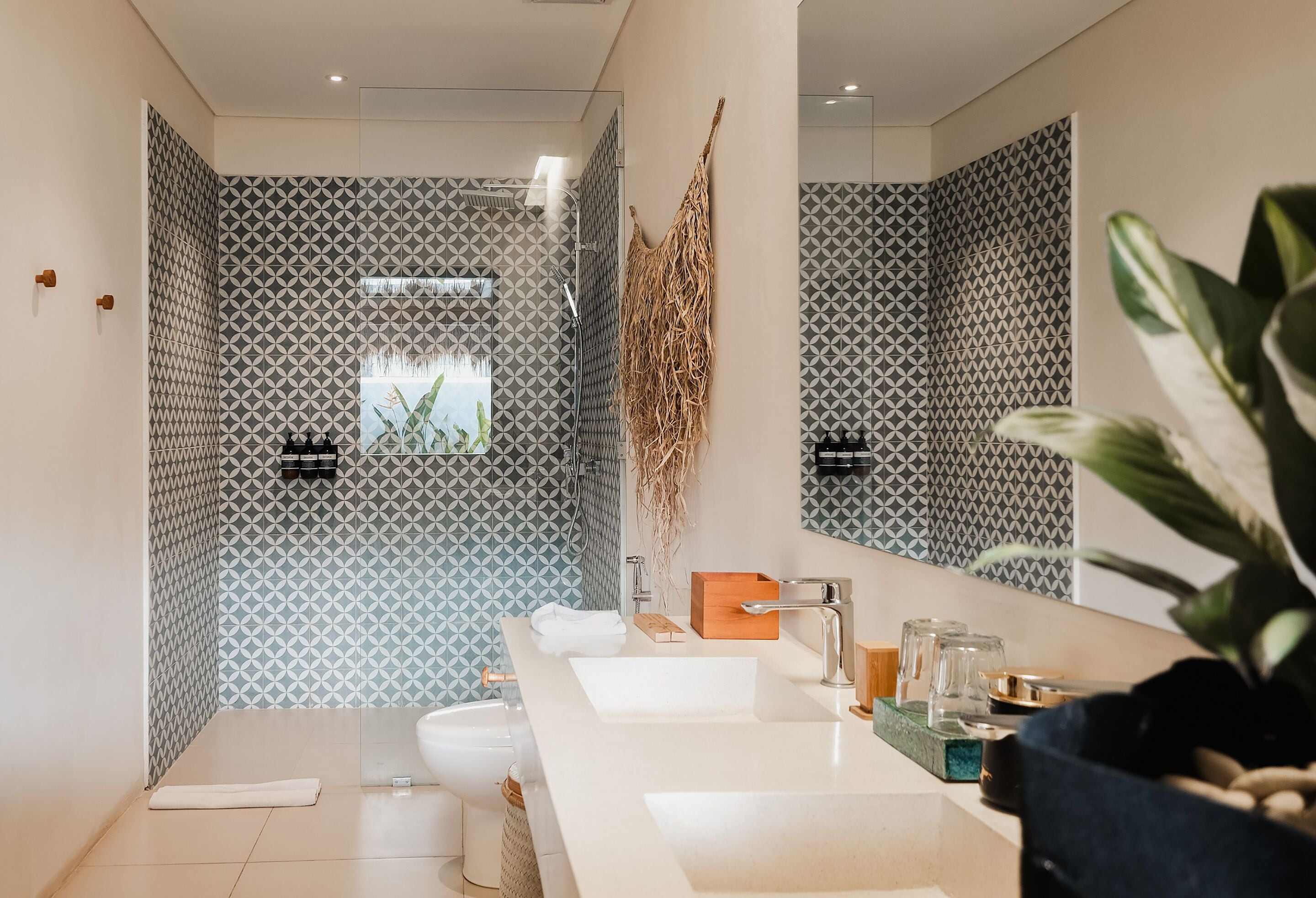 A modern bathroom with patterned walls, a large mirror, and a white vanity with multiple sinks.