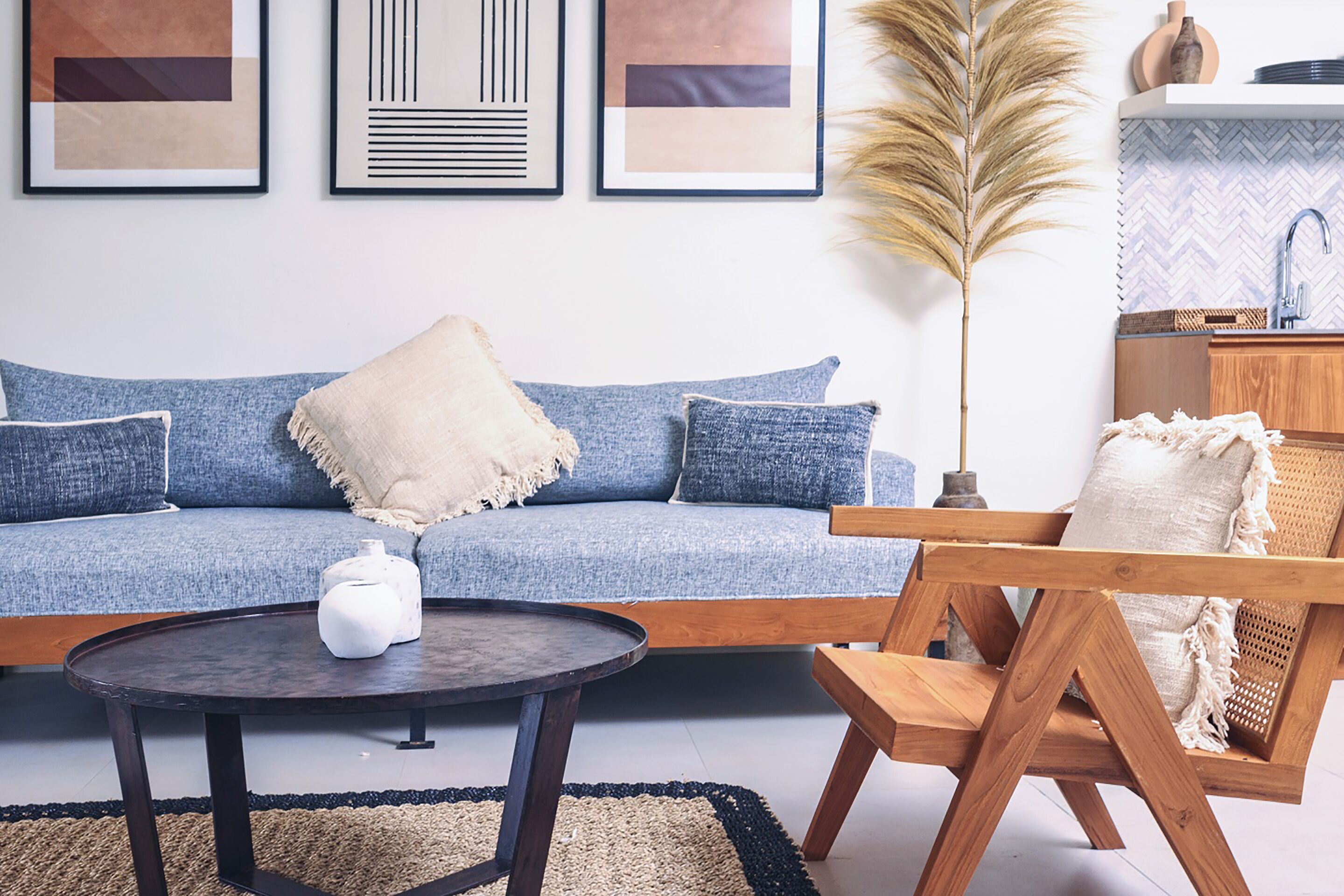 A living room with a blue sofa, a round coffee table, and a wooden chair.