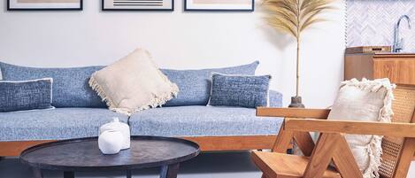 A living room with a blue sofa, a round coffee table, and a wooden chair.
