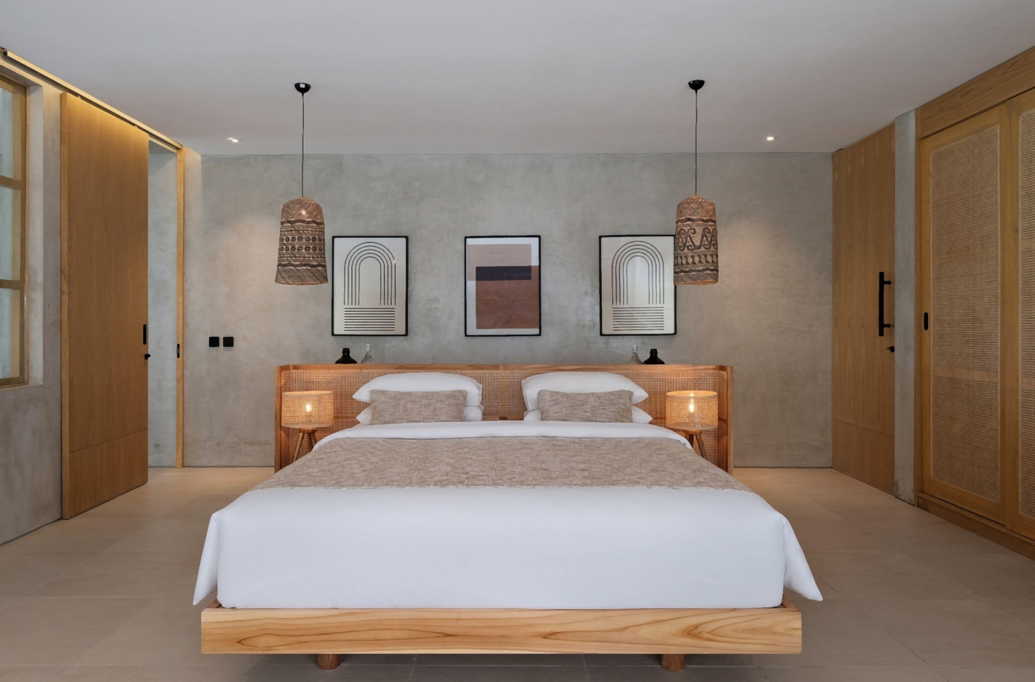 Une chambre à coucher moderne avec un grand lit, deux tables de chevet avec des lampes et trois œuvres d’art encadrées accrochées au mur.