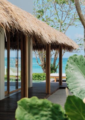 A wooden deck with a thatched roof structure, overlooking a clear blue sea. - Amber Lombok Beach Resort (Selong Belanak)