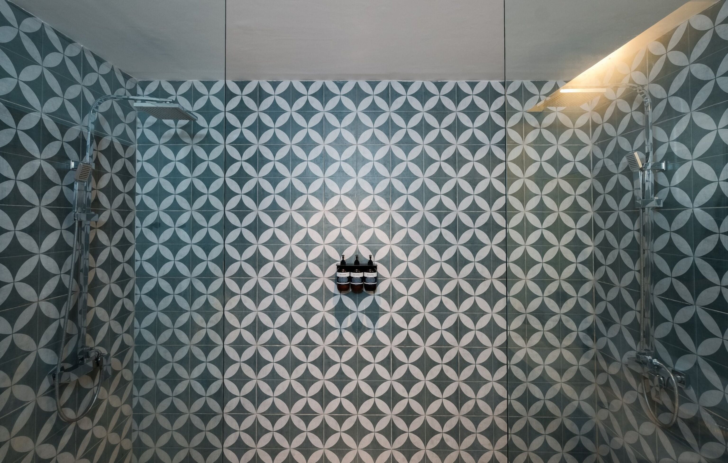 A shower with a geometric tile pattern and a visible drain.