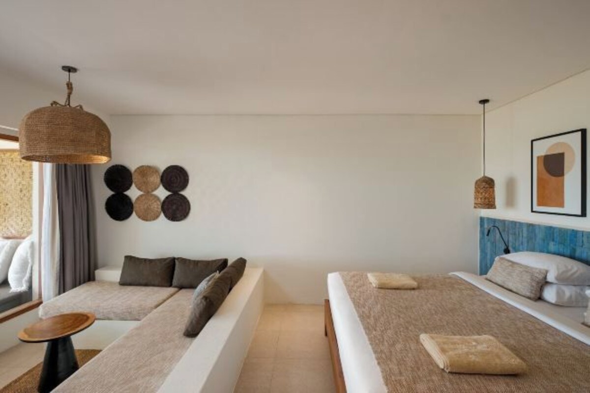 Una habitación de hotel moderna con un sofá, una cama, una mesita y decoración en la pared.
