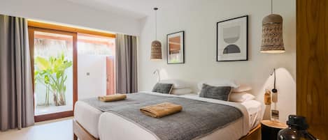 A modern bedroom with a large bed, two bedside tables, a nightstand, and a hanging lamp.