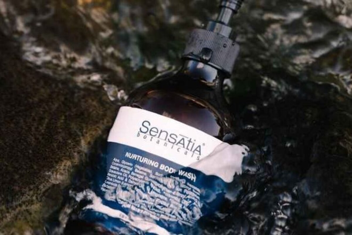 Una botella de Sensatia Botanicals Nurturing Body Wash en un entorno natural.