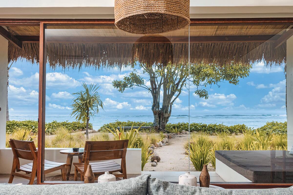 A modern outdoor seating area with wooden furniture and a view of the ocean.