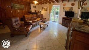Ein gemütliches Wohnzimmer mit Ledersofa, Holzwänden und einem Fernseher.