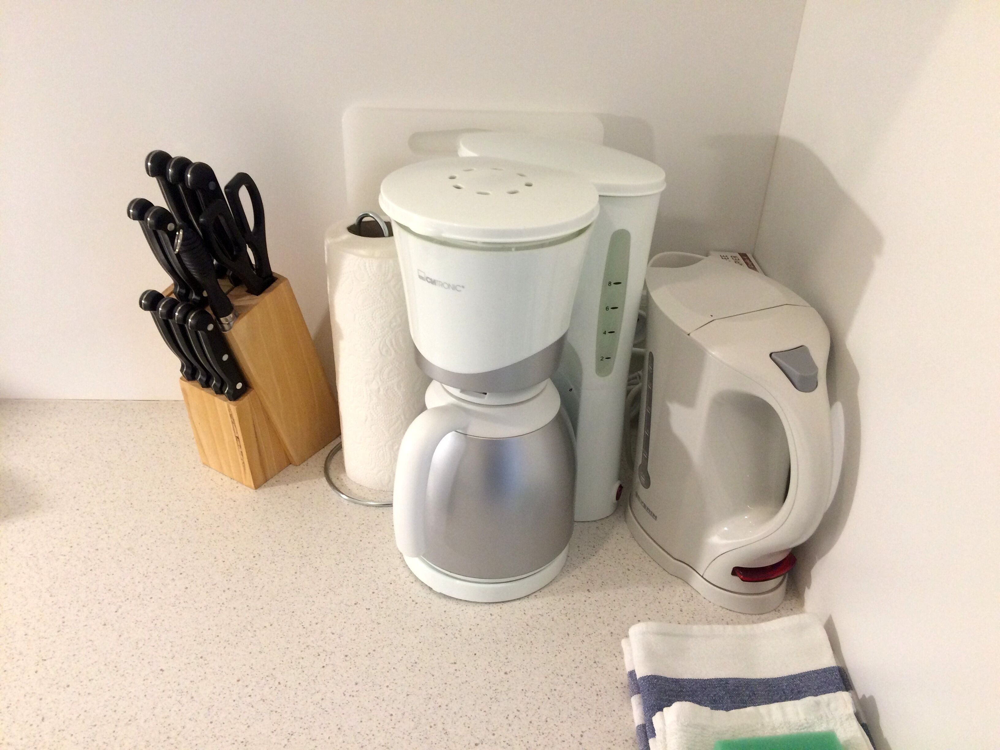 A kitchen with a coffee maker, kettle, and knife block.