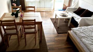 Una habitación con una mesa de madera, sillas, un sofá y una cama.