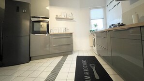 A modern kitchen with stainless steel appliances, a built-in oven, and a washing machine. - Premium city apartment * underground parking, Netflix, Prime * (Cottbus)