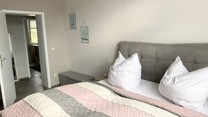 A bedroom with a bed, pillows, a bedside table, and a wall with two motivational signs. - Premium city apartment * underground parking, Netflix, Prime * (Cottbus)