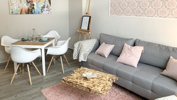 A modern living room with a grey sofa, white chairs, a wooden coffee table, and a painting of a deer on the wall. - Premium city apartment * underground parking, Netflix, Prime * (Cottbus)