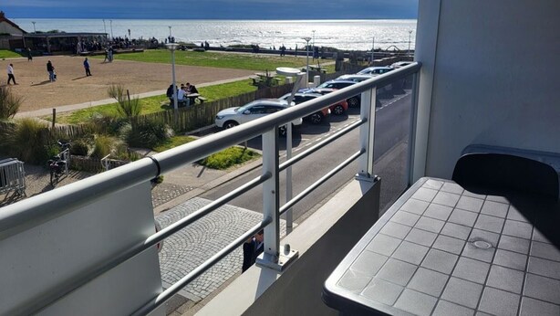 A balcony with a view of a beach, a parking area, and a dining area. - Studio 100m from the Sea in Saint-Hilaire-de-Riez, with Balcony and Public Parking (Saint-Hilaire-de-Riez)