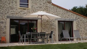 A stone building with a dining area featuring a table, chairs, and an umbrella.