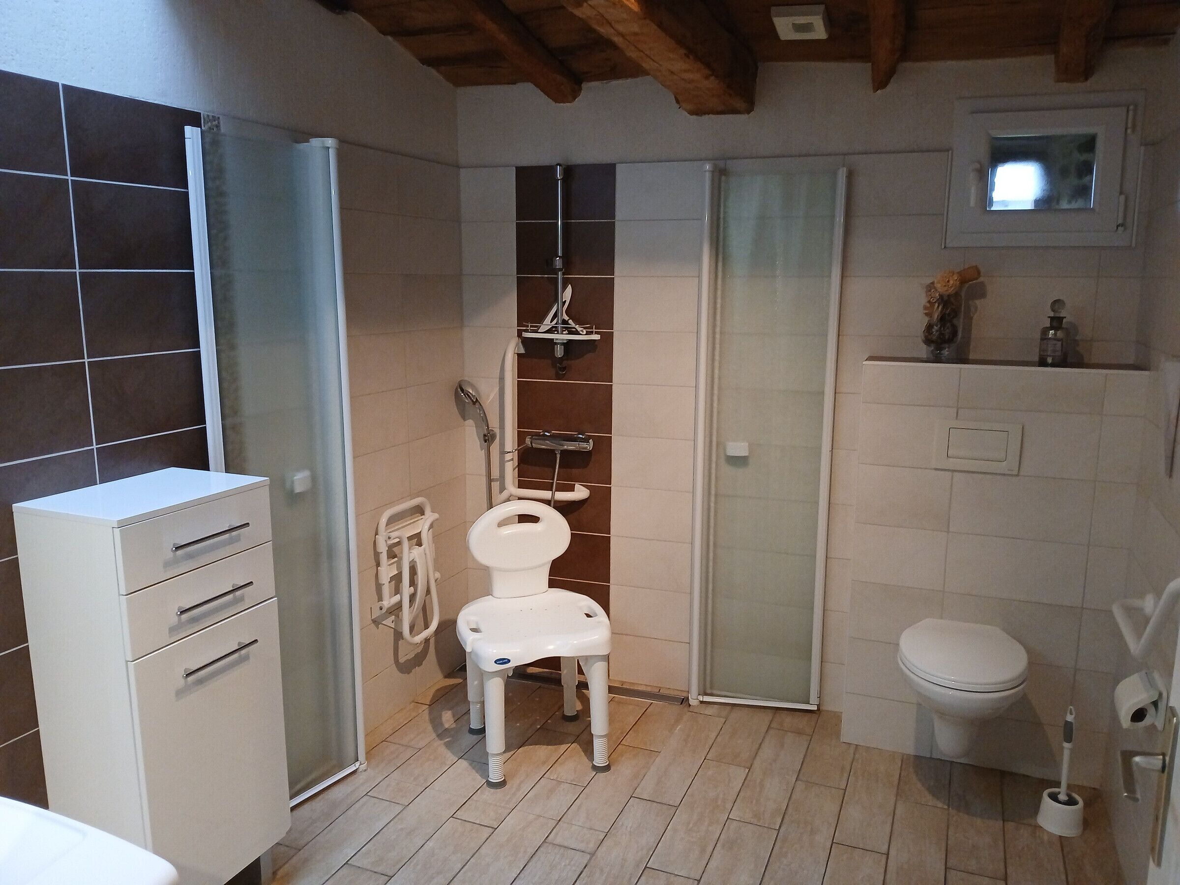 A bathroom with a toilet, a shower enclosure, and a cabinet.