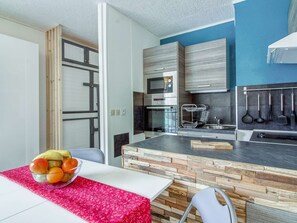Uma cozinha moderna com painel de pedra, forno embutido e diversos utensílios de cozinha pendurados na parede.
