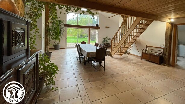 Une salle à manger spacieuse avec un plafond en bois, un escalier et une vue sur l’extérieur.