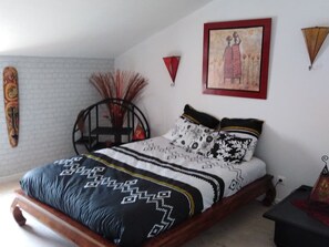 A bedroom with a bed, a chair, a wall art piece, and a decorative wall hanging. - Family Retreat with Heated Pool, Near Puy du Fou & La Rochelle, Sleeps 14 (L'Hermenault)
