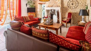 A cozy living room with a brown sofa, red cushions, a wooden coffee table, and a stone wall.