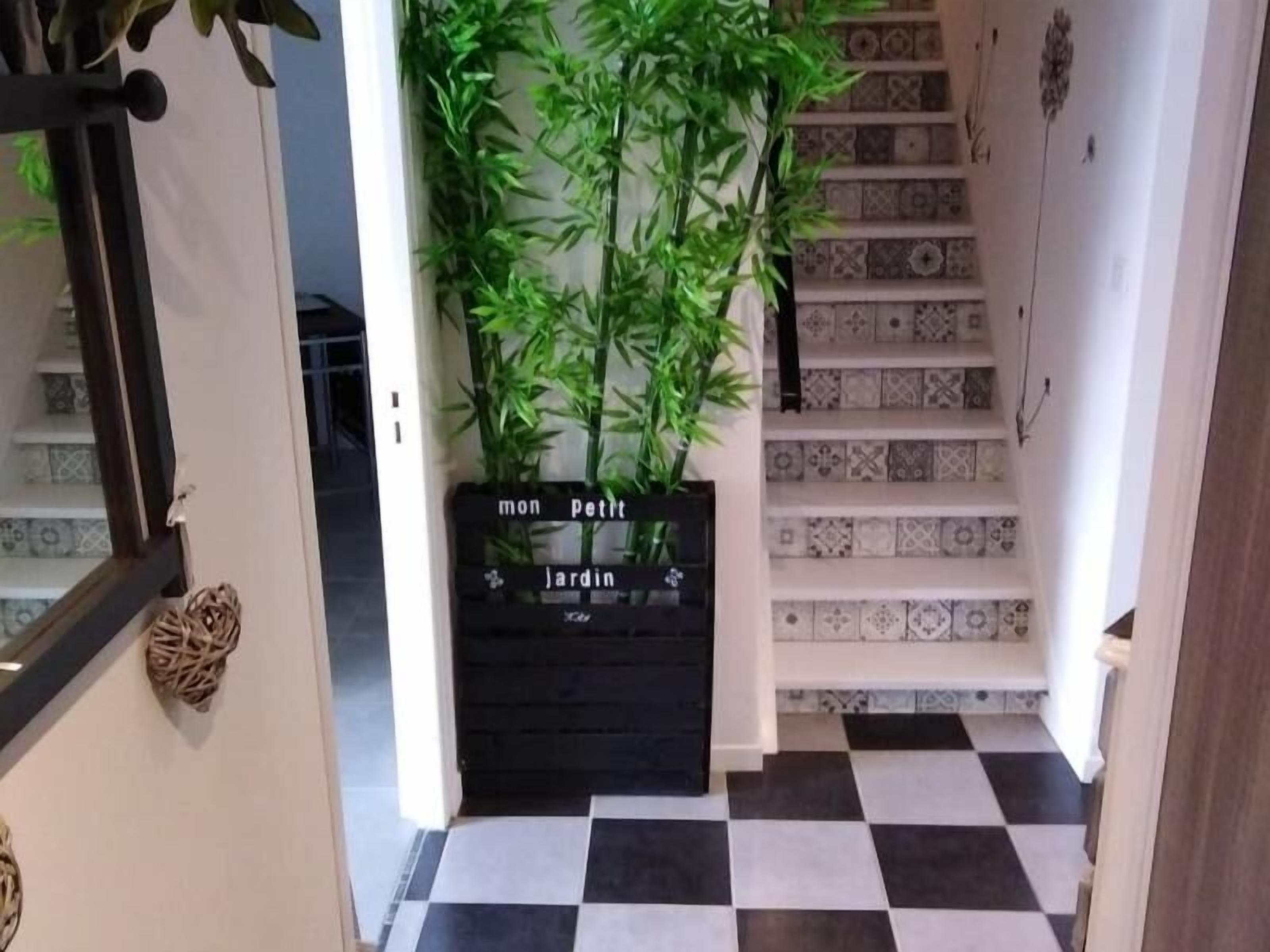 A staircase with patterned tiles, a black and white checkered floor, and a sign reading "mon petit jardin" with a plant beside it.