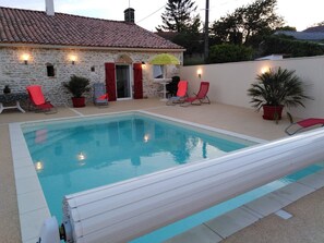 A swimming pool with red lounge chairs and a stone building with a tiled roof. - Family Retreat with Heated Pool, Near Puy du Fou & La Rochelle, Sleeps 14 (L'Hermenault)