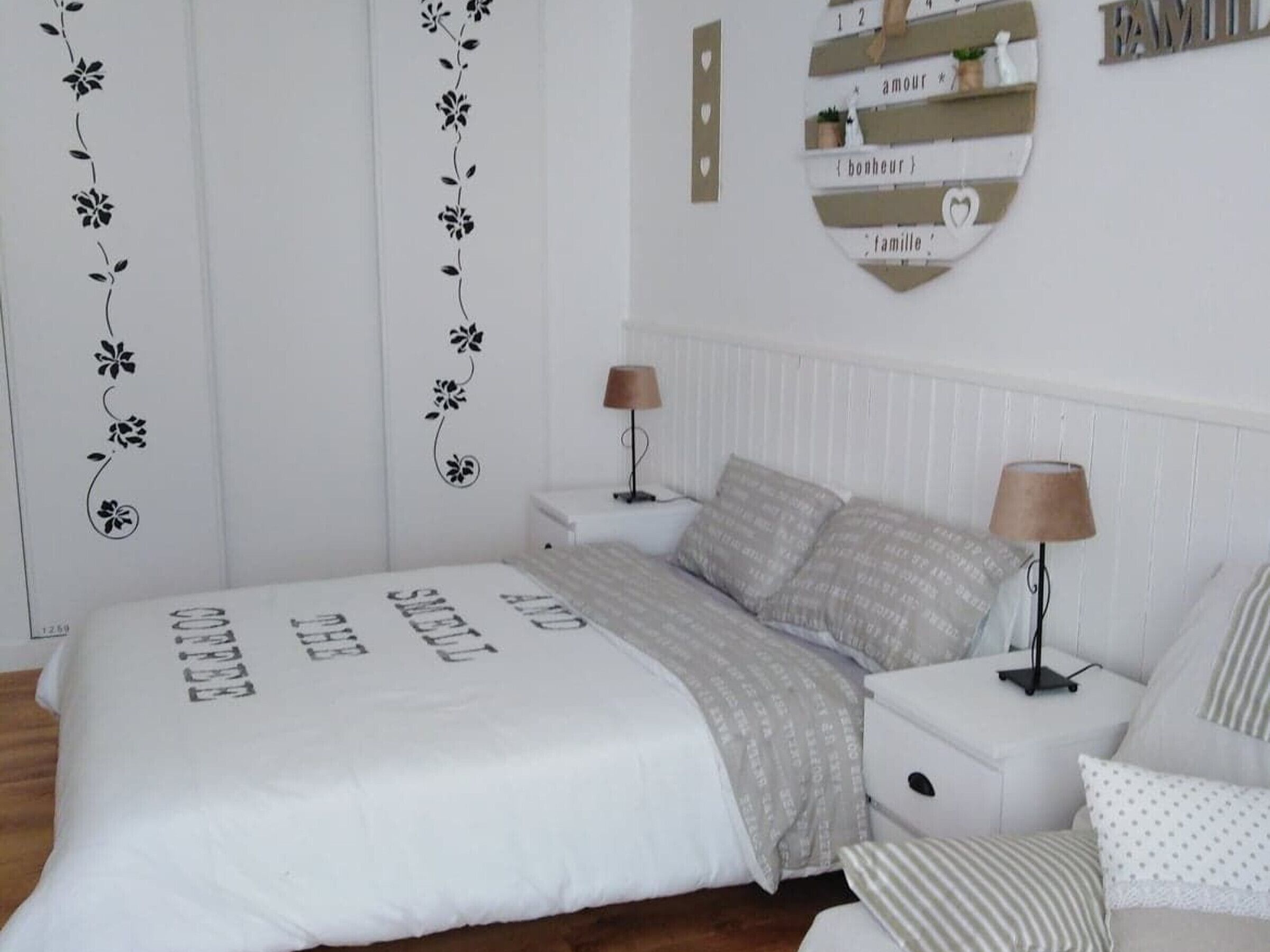 Ein Schlafzimmer mit einem Bett, zwei Nachttischen, einer Lampe, einer Kommode und einer Wanddekoration.