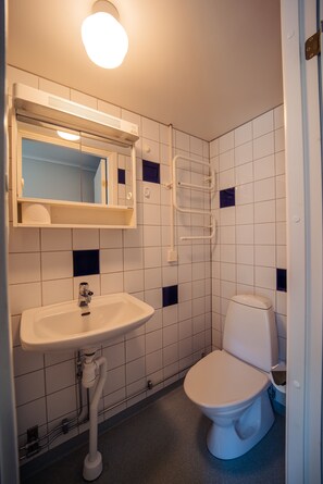 Ein kleines Badezimmer mit einem weißen Waschbecken, einem Spiegel und einer weißen Toilette.