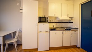 A compact kitchen with white cabinets, a microwave, a refrigerator, and a stove.