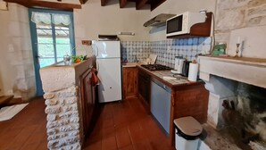 A compact kitchen with a refrigerator, stove, microwave, and tiled backsplash.