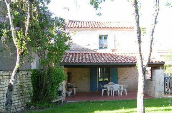 A rustic stone building with a tiled roof, a small patio with outdoor seating, and a date stamp of 08.04.2011. - Charming 1900s House in Marais Poitevin with Garden, Terrace, and Fishing Access (Benet)