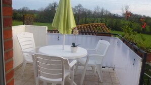 A small outdoor patio with a round table, two white chairs, and a green umbrella. - Rustic cottage with games room and animals in the countryside (Saint-Julien-des-Landes)