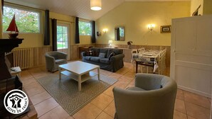 A cozy living room with a white coffee table, two sofas, and a dining table with chairs. There is a window with curtains, a radiator, and a door. - Charming Renovated House with Private Pool in Saint-Christophe-du-Ligneron (Saint-Christophe-du-Ligneron)