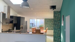 Et moderne køkken med ovenlys, et spiseområde med bord og stole, og en grøn accentvæg.