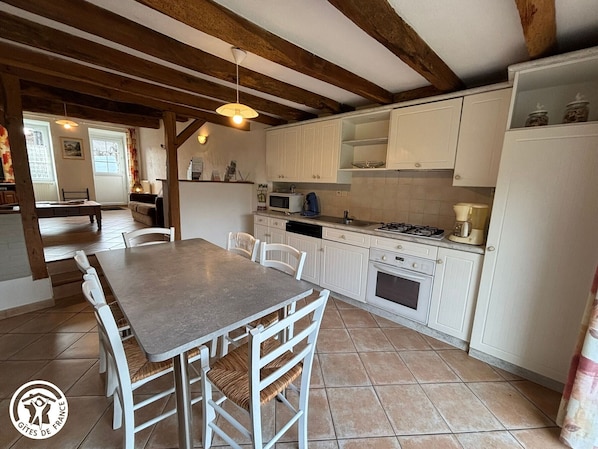 A kitchen with white cabinets, a dining table with chairs, a stove, and a microwave.