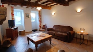 Un salon chaleureux avec un canapé en cuir marron, une table basse en bois et un téléviseur posé sur un meuble en bois.