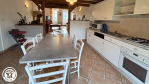 Une cuisine avec des meubles blancs, une table à manger avec des chaises, un four à micro-ondes et une cuisinière.