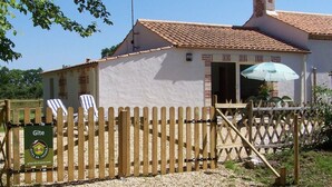 A house with a tiled roof, a wooden fence, and a sign for Gîte de France. - Cozy Traditional Cottage with Private Garden, Near La Garnache (La Garnache)