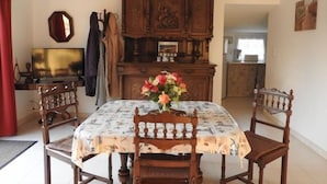 A dining room with a wooden table, chairs, a floral centerpiece, and a large wooden cabinet with carvings. - Cozy Traditional Cottage with Private Garden, Near La Garnache (La Garnache)