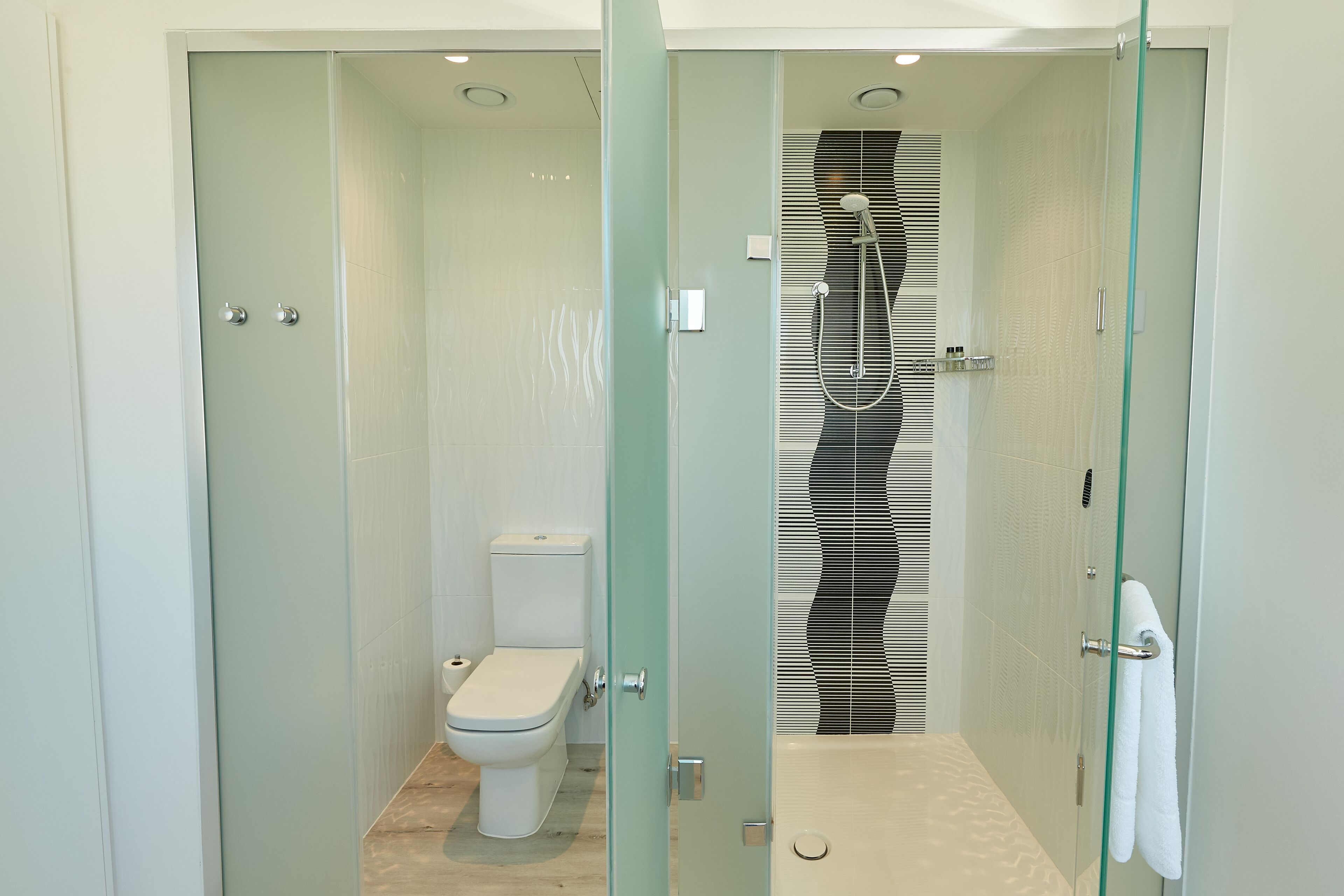 A modern bathroom with a glass-enclosed shower, a toilet, and a bathtub.