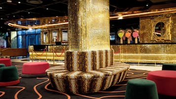 A lobby with a central column, red and green ottomans, and a decorative mirror.
