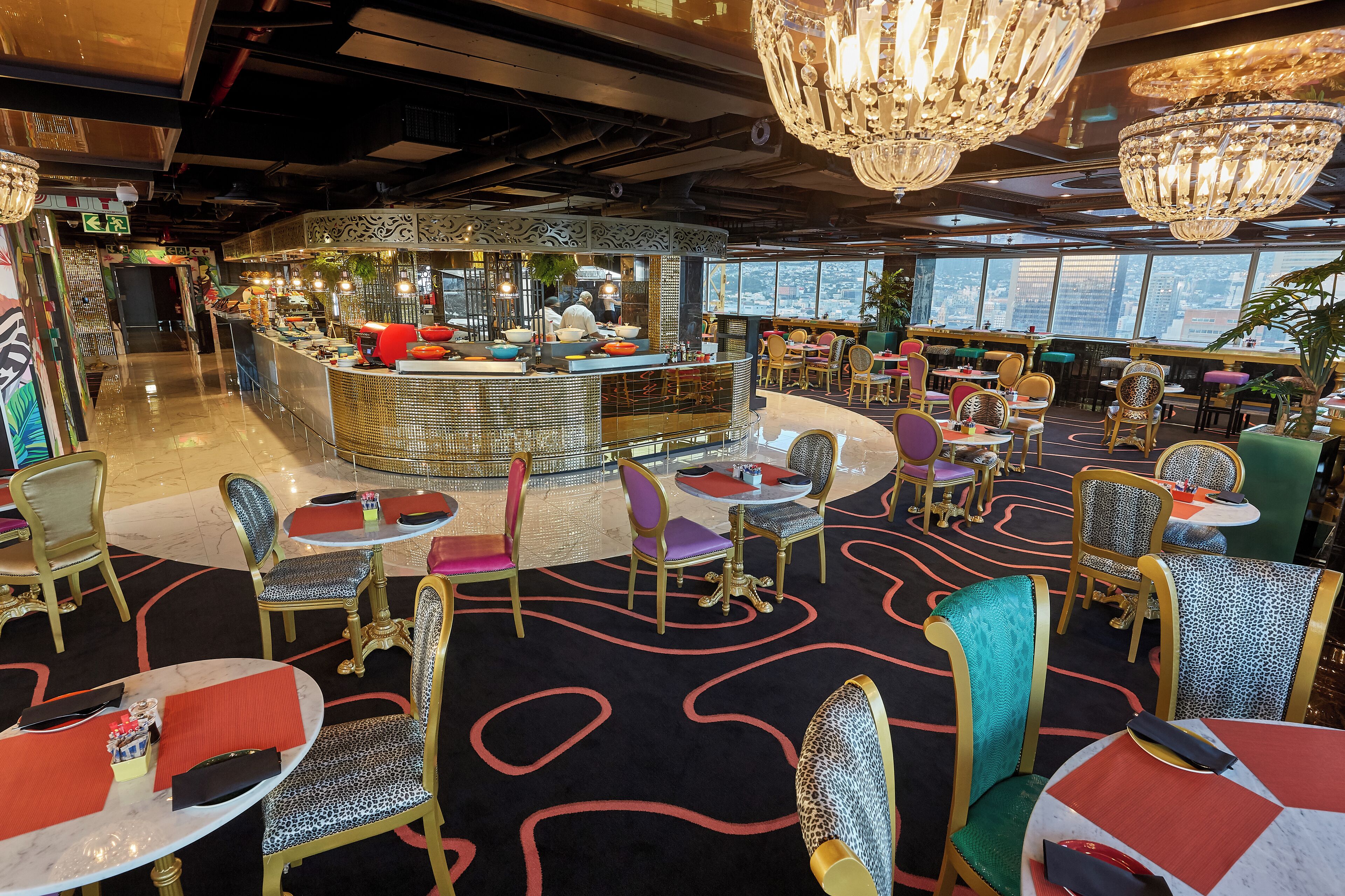 A modern restaurant with a central bar, round tables, and chairs with patterned upholstery.