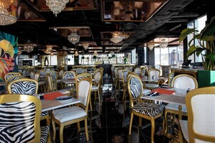 Un restaurante con sillas a rayas de cebra, candelabros y vistas de la ciudad.