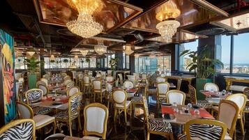 A restaurant with zebra-patterned chairs, chandeliers, and a city view.