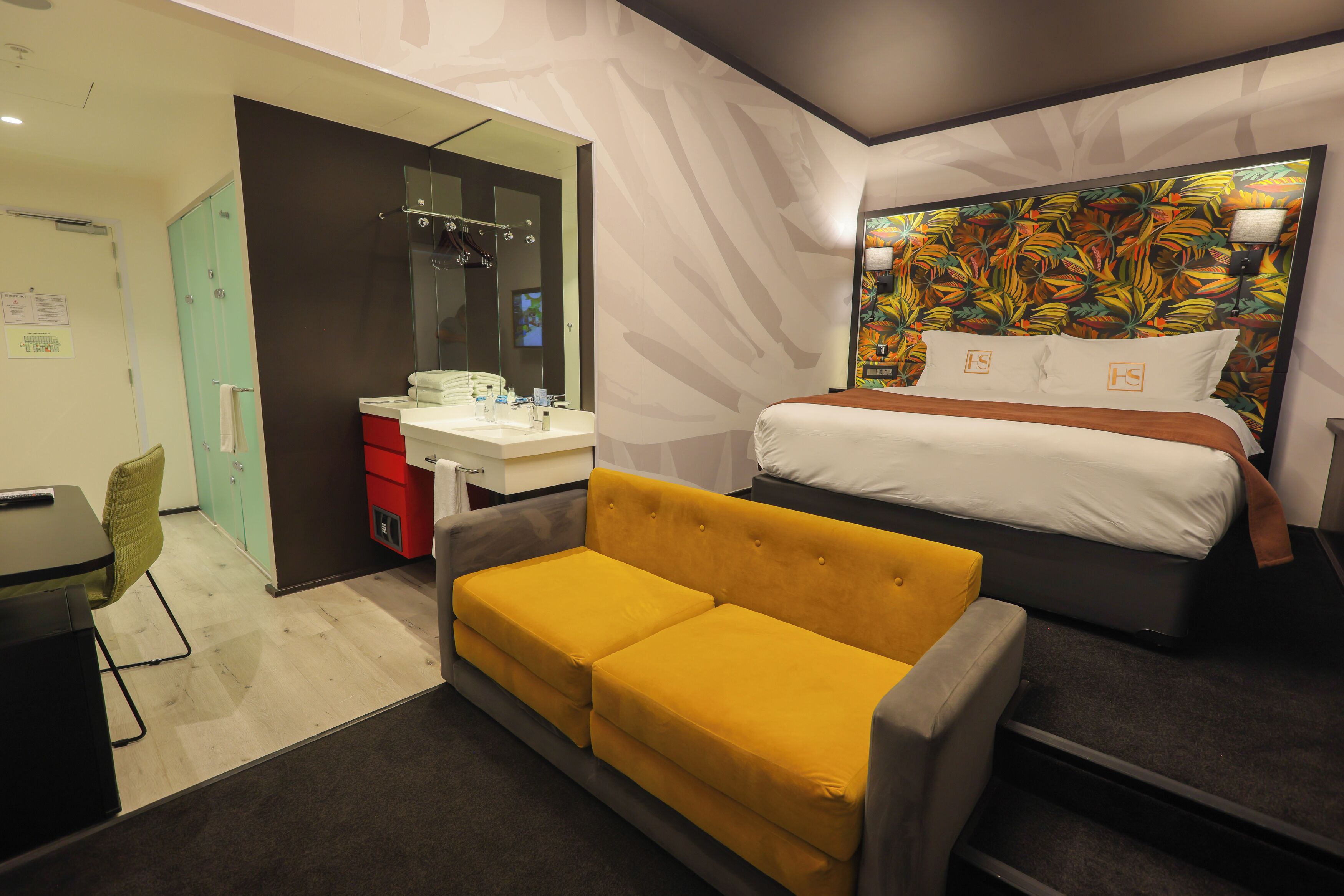 Una habitación de hotel con cama, sofá, escritorio y baño.