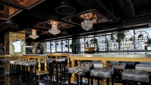 A bar with high stools, chandeliers, and a view of the city. - Hotel Sky Cape Town (Cape Town)
