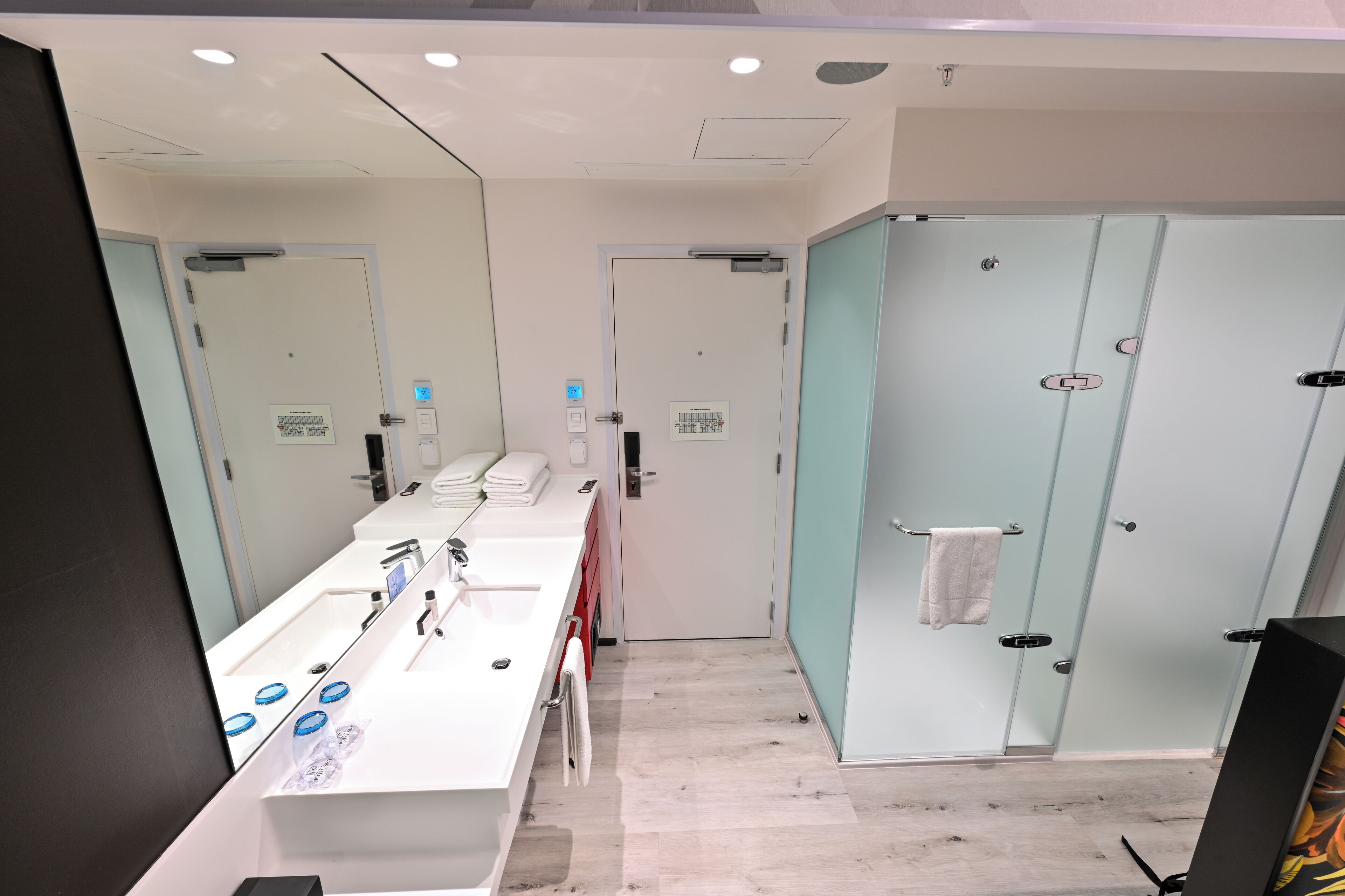 A modern bathroom with a long vanity, a mirror, and a glass shower enclosure.