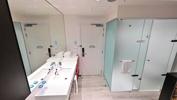 Une salle de bain moderne avec un long meuble-lavabo, un miroir et une cabine de douche en verre.