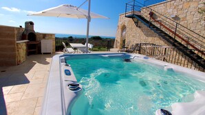 Uma piscina com parede de pedra e vista para o mar.